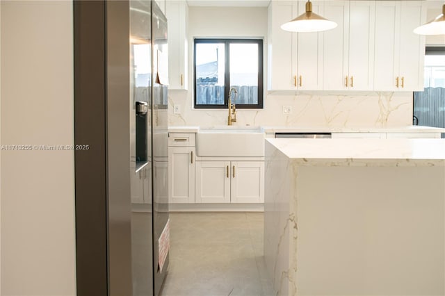 kitchen featuring pendant lighting, white cabinets, sink, decorative backsplash, and light stone counters