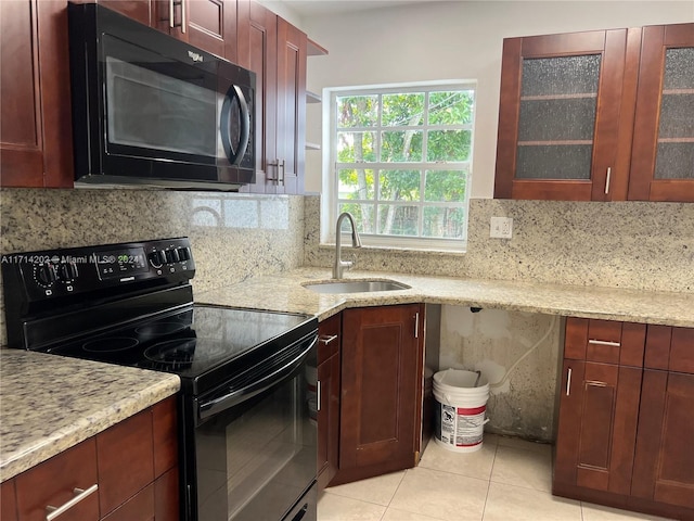 kitchen with light stone countertops, sink, decorative backsplash, light tile patterned floors, and black appliances