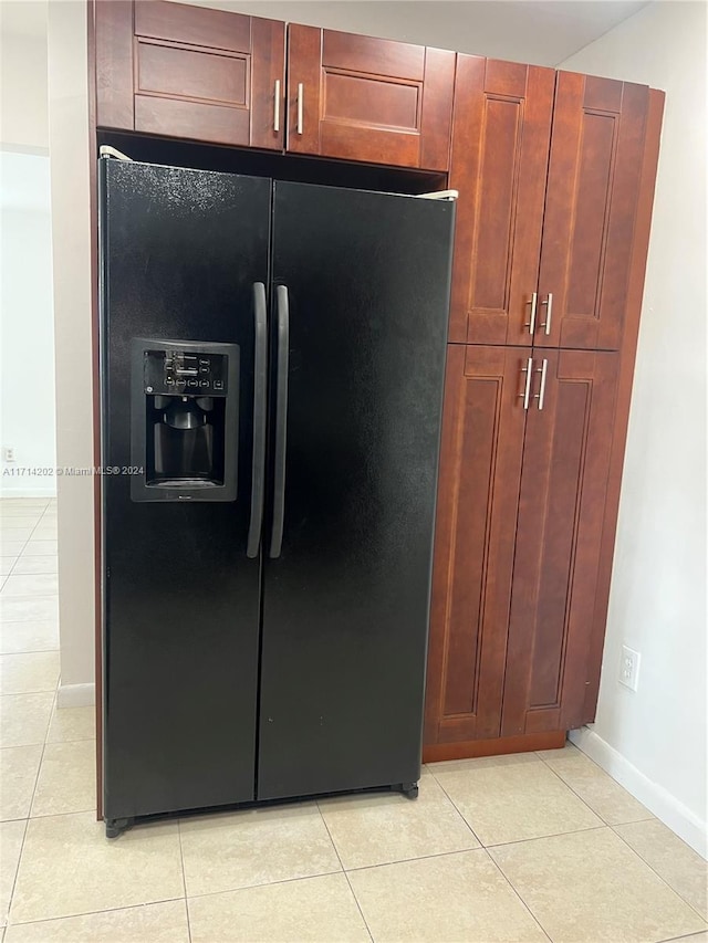 kitchen with black refrigerator with ice dispenser and light tile patterned flooring