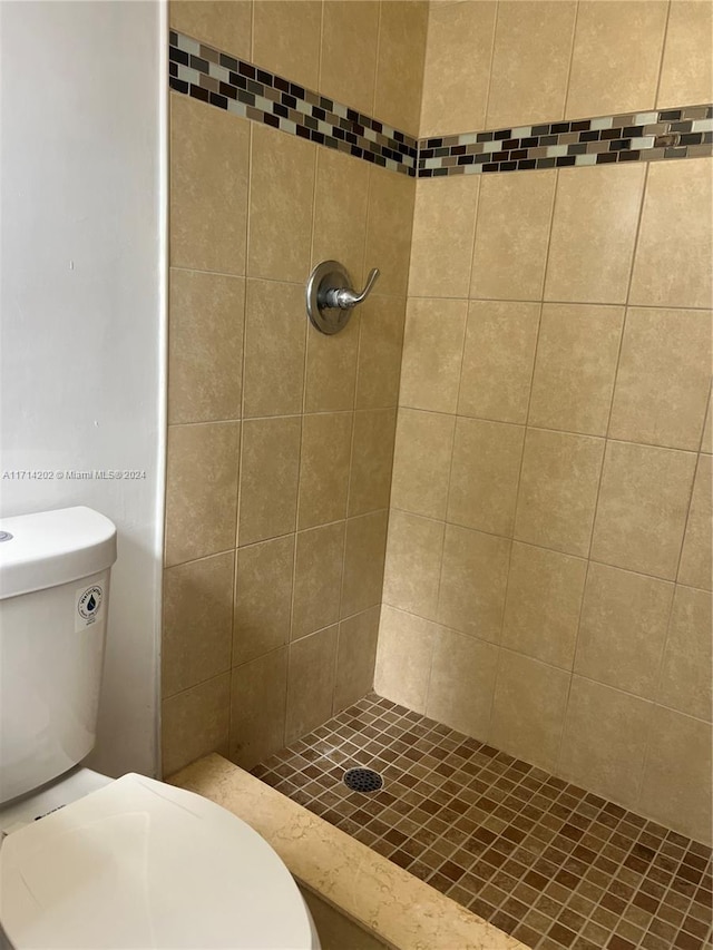 bathroom featuring a tile shower and toilet