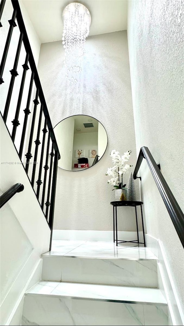 stairs with a notable chandelier