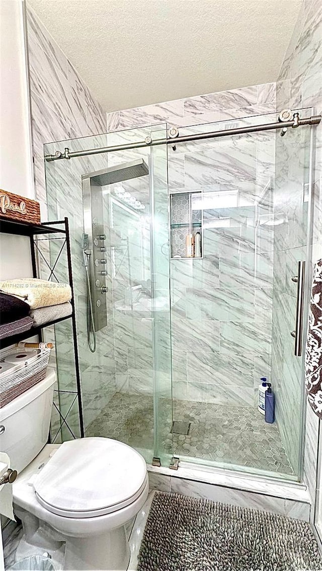 bathroom featuring a textured ceiling, toilet, and walk in shower