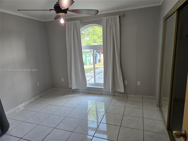 empty room with light tile patterned floors, ceiling fan, and ornamental molding