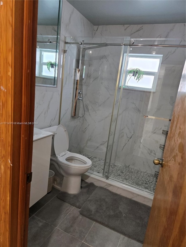 bathroom with tile patterned flooring, toilet, a shower with shower door, and tile walls