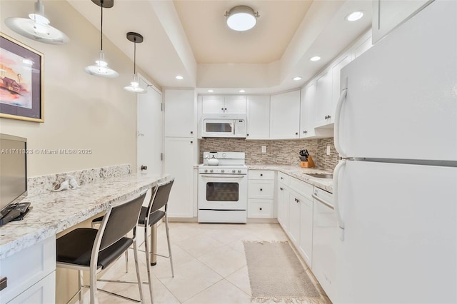 kitchen with hanging light fixtures, white appliances, white cabinets, and light tile patterned flooring