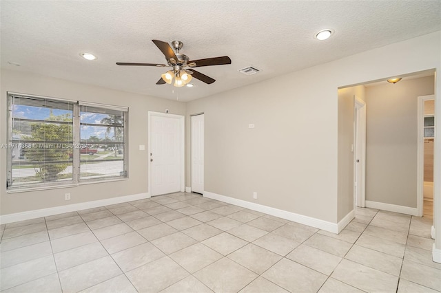 tiled empty room featuring ceiling fan and a textured ceiling