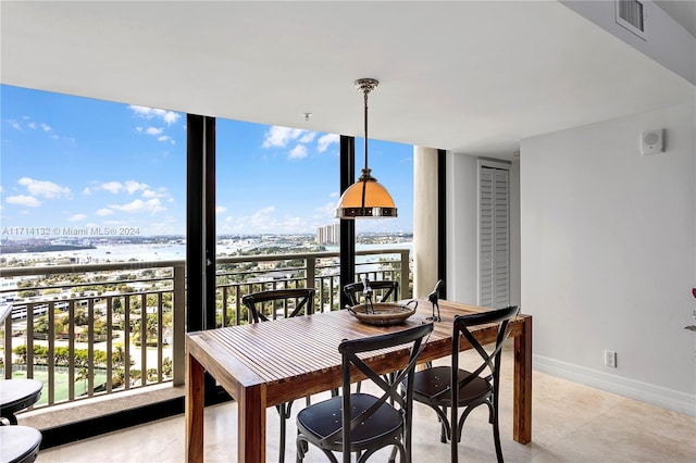 dining room with a wealth of natural light, a water view, and expansive windows