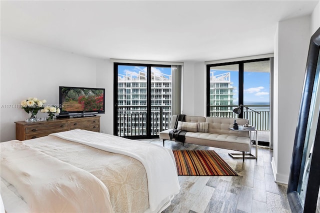 bedroom featuring access to outside, light hardwood / wood-style flooring, and expansive windows