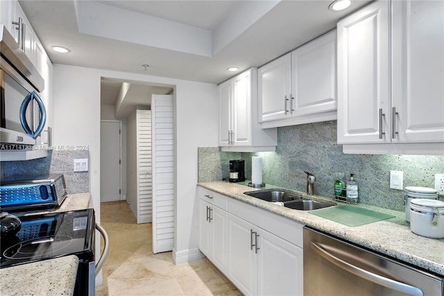 kitchen featuring backsplash, white cabinets, sink, light stone countertops, and stainless steel appliances