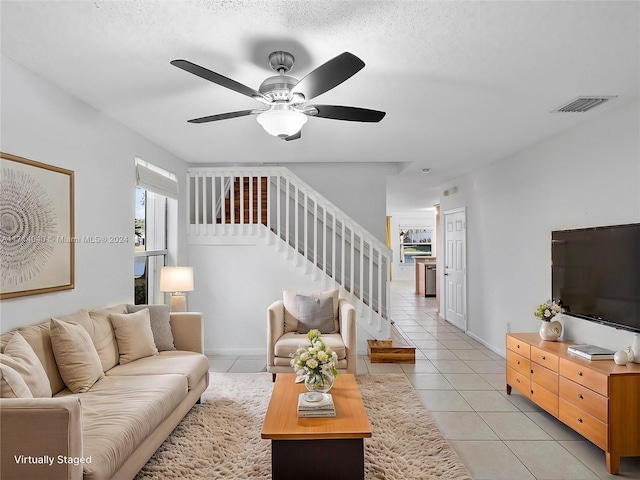 living room with light tile patterned floors, a textured ceiling, and ceiling fan