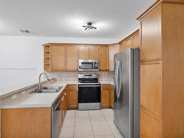 kitchen featuring sink, decorative backsplash, a textured ceiling, light tile patterned flooring, and stainless steel appliances