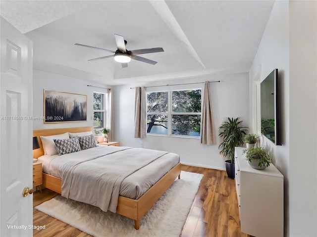 bedroom featuring hardwood / wood-style flooring, ceiling fan, and a raised ceiling