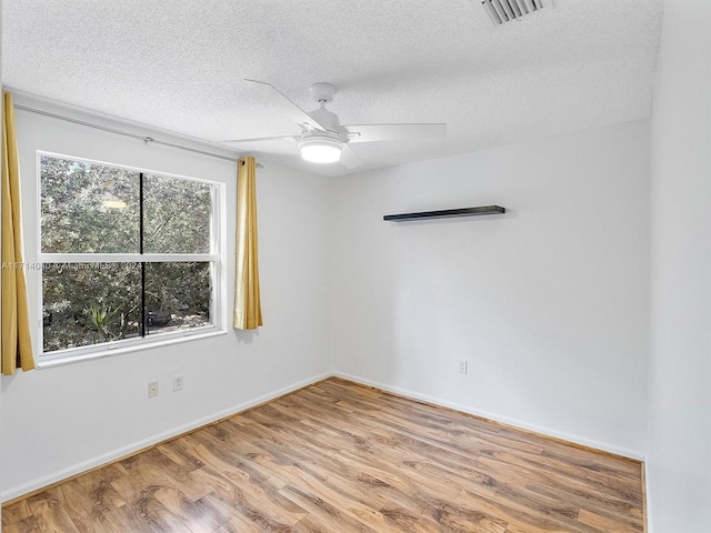 empty room with ceiling fan, light hardwood / wood-style floors, and a textured ceiling