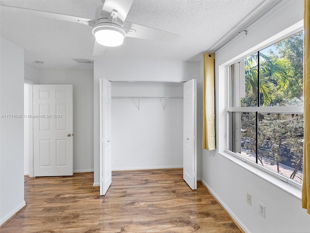 unfurnished bedroom featuring hardwood / wood-style flooring, ceiling fan, a closet, and multiple windows