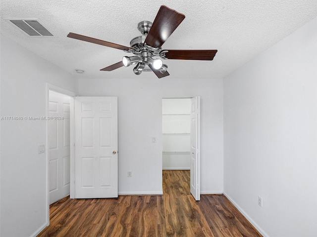 unfurnished bedroom with a closet, ceiling fan, dark hardwood / wood-style flooring, and a textured ceiling