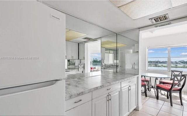 kitchen featuring white cabinets, light tile patterned floors, white fridge, and white fridge with ice dispenser