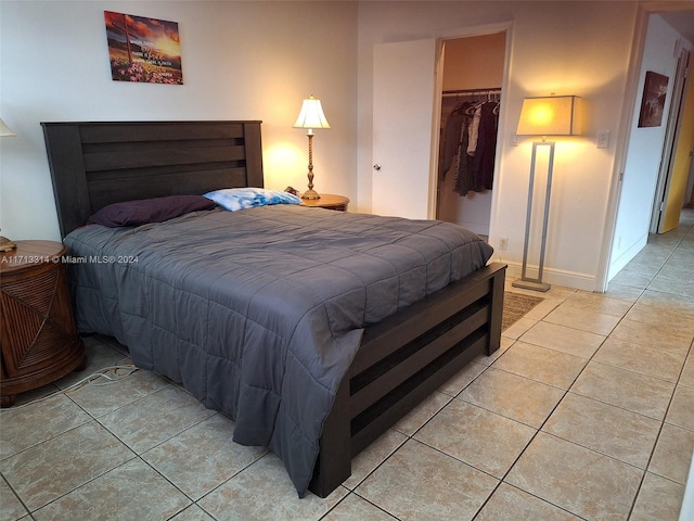 bedroom featuring a spacious closet, light tile patterned floors, and a closet