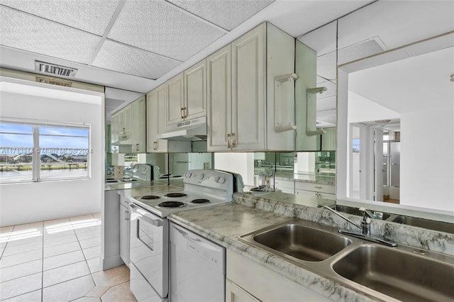 kitchen featuring a drop ceiling, white appliances, sink, and light tile patterned floors