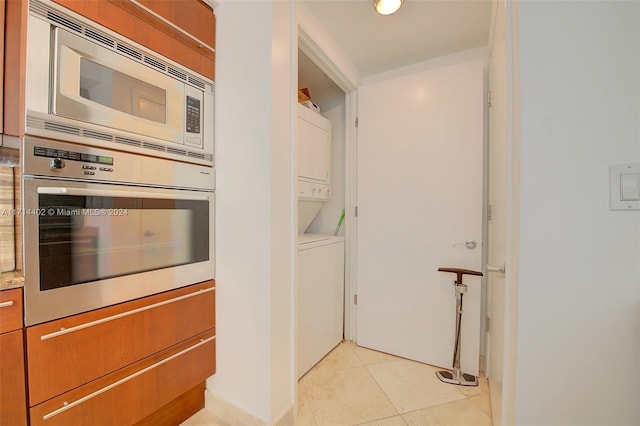 kitchen featuring appliances with stainless steel finishes, stacked washing maching and dryer, and light tile patterned floors