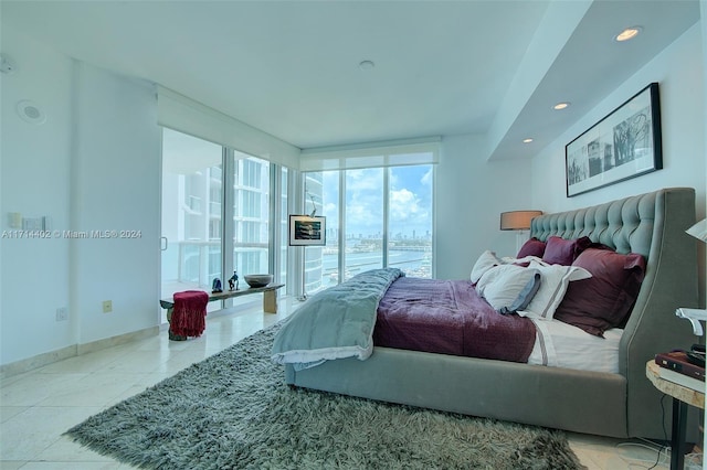 tiled bedroom featuring a water view and a wall of windows