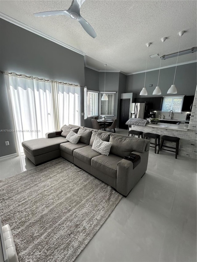 living room with a textured ceiling, a ceiling fan, and crown molding