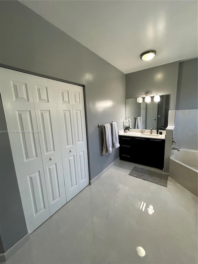 bathroom featuring a bath, double vanity, baseboards, and a closet