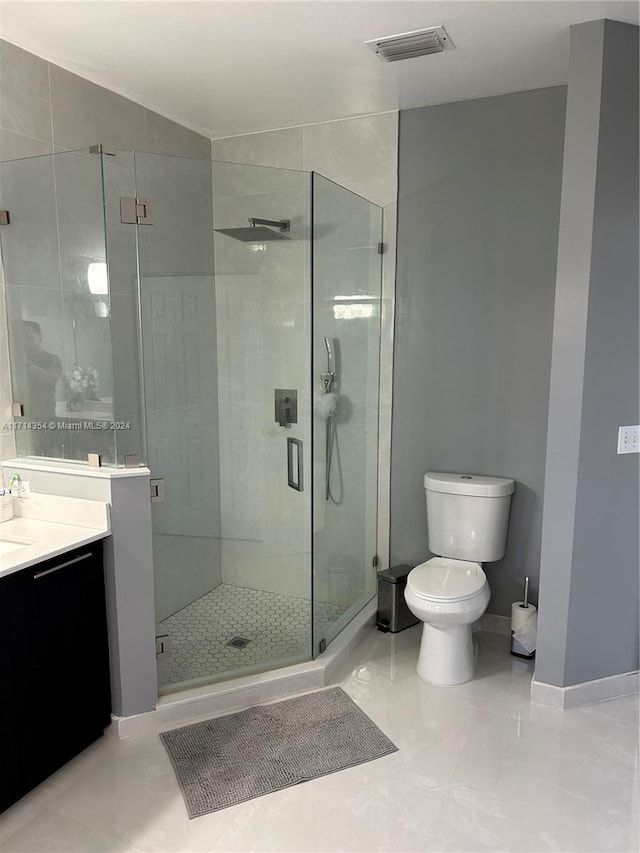 bathroom with tile patterned floors, vanity, an enclosed shower, and toilet