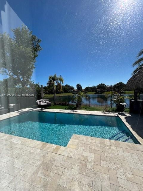 view of pool with a patio and a water view