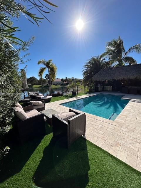 pool with a water view, a patio, and an outdoor hangout area