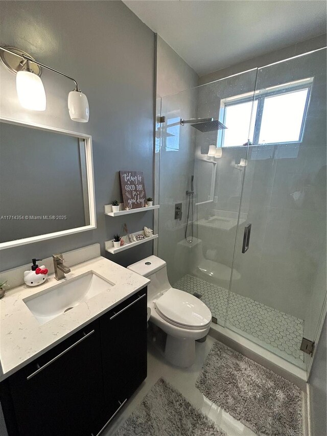 bathroom with a stall shower, vanity, and toilet