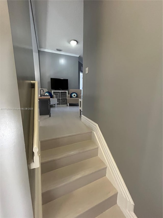 staircase featuring crown molding and a textured ceiling