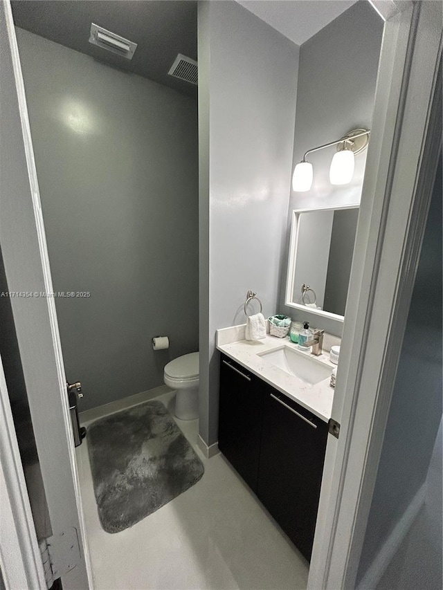 bathroom featuring baseboards, visible vents, vanity, and toilet