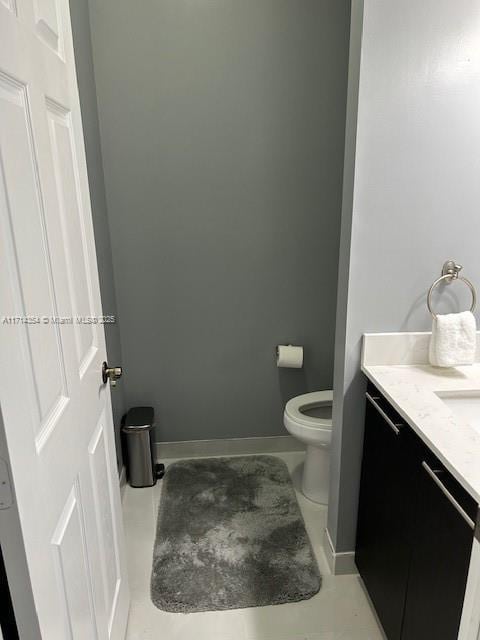 half bath with vanity, toilet, and baseboards