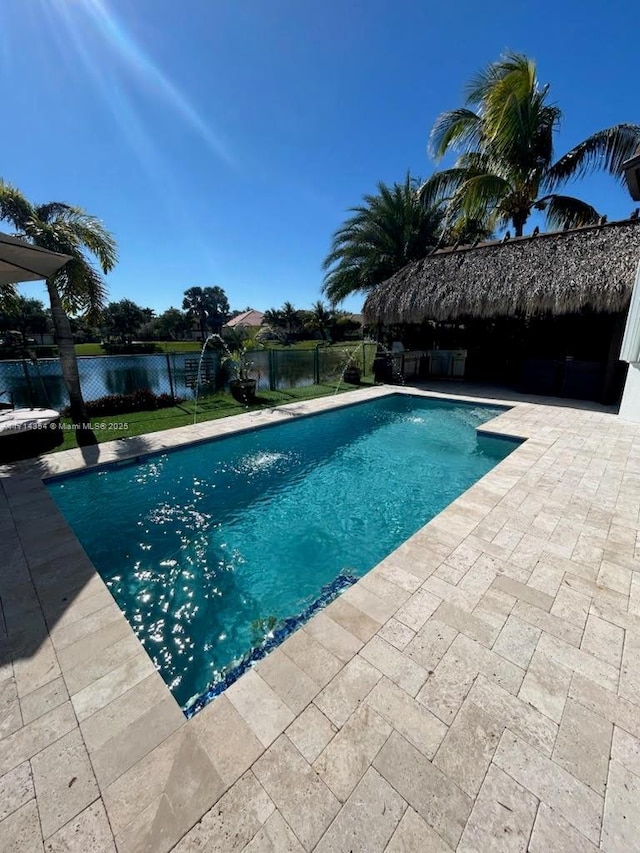 view of swimming pool with a water view, a patio area, fence, and a fenced in pool