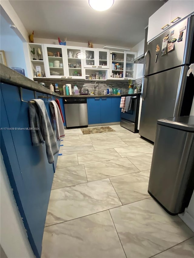 kitchen with sink, blue cabinetry, appliances with stainless steel finishes, tasteful backsplash, and white cabinetry