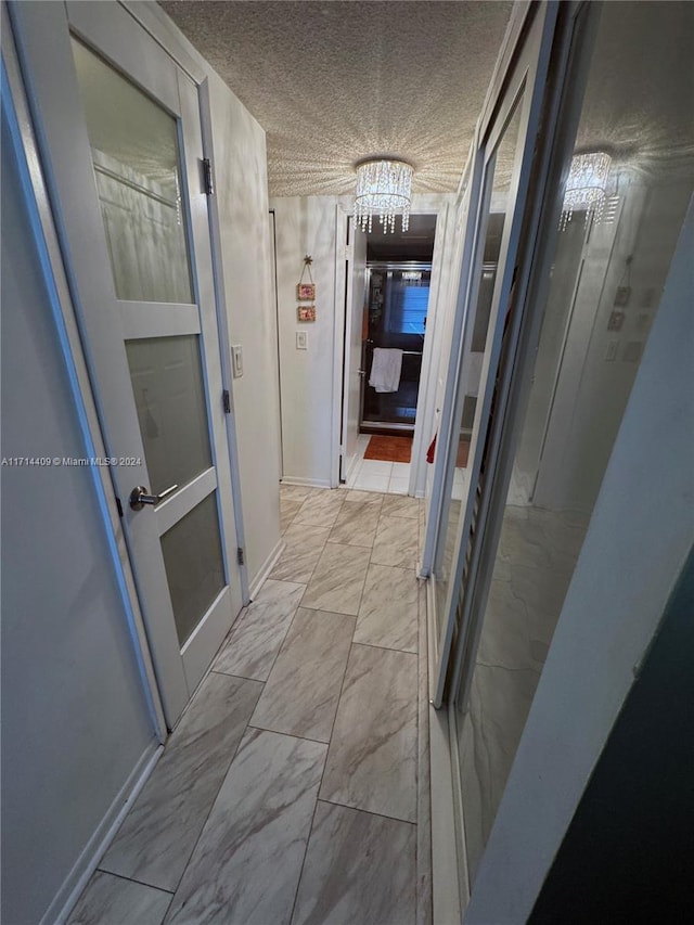 hall featuring a chandelier and a textured ceiling