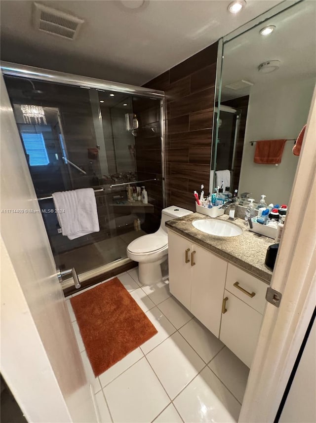 bathroom featuring tile patterned floors, a shower with door, vanity, and toilet