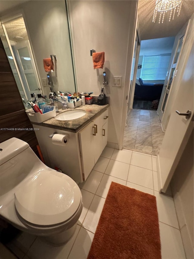 bathroom featuring tile patterned floors, vanity, a notable chandelier, and toilet