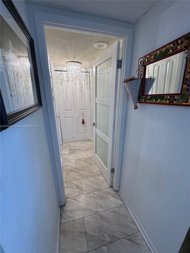 hallway with a notable chandelier and a textured ceiling