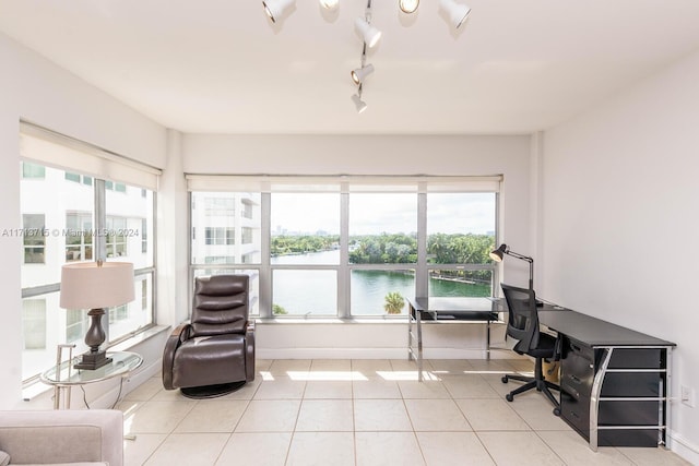 office space with a healthy amount of sunlight, a water view, light tile patterned floors, and track lighting