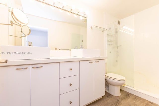 bathroom featuring hardwood / wood-style flooring, vanity, toilet, and a shower with shower door