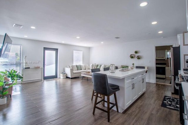 kitchen with a kitchen breakfast bar, white cabinets, range, a center island, and dark hardwood / wood-style floors