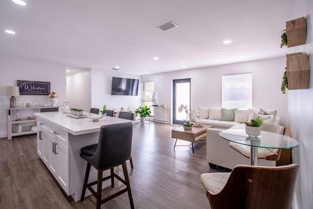 kitchen with a center island, dark hardwood / wood-style flooring, white cabinetry, and a breakfast bar area