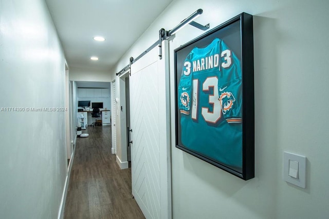 corridor with a barn door and hardwood / wood-style floors