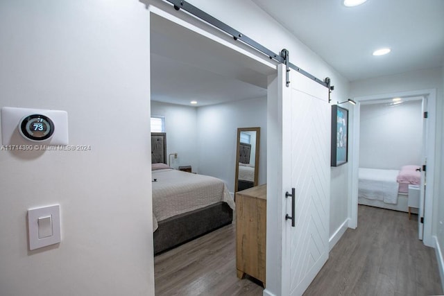 bedroom with a barn door and hardwood / wood-style floors