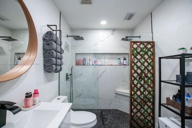 bathroom with a tile shower, vanity, and toilet