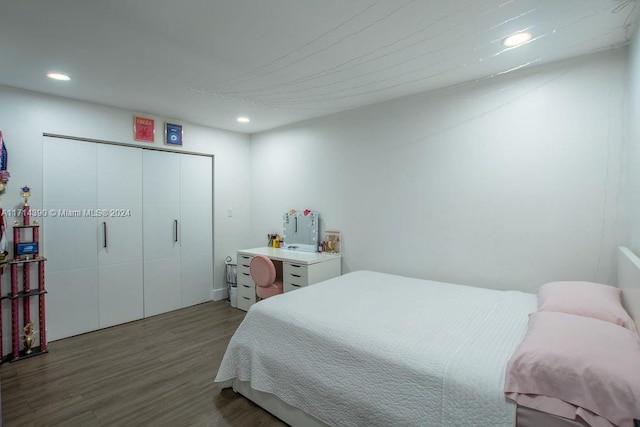 bedroom with dark hardwood / wood-style flooring and a closet