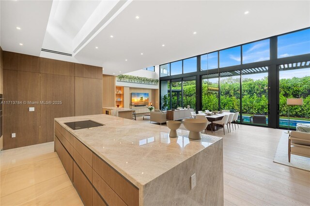 kitchen featuring sink, a breakfast bar area, light hardwood / wood-style flooring, a high ceiling, and light stone counters