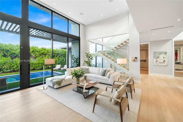 living room featuring a high ceiling, floor to ceiling windows, and light hardwood / wood-style floors