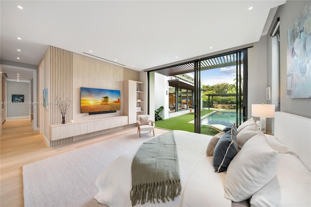 bedroom featuring a wall of windows, light wood-type flooring, and access to outside